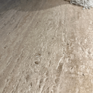 Detailfoto van een travertin tafelblad met natuurlijke aders en kleurnuances