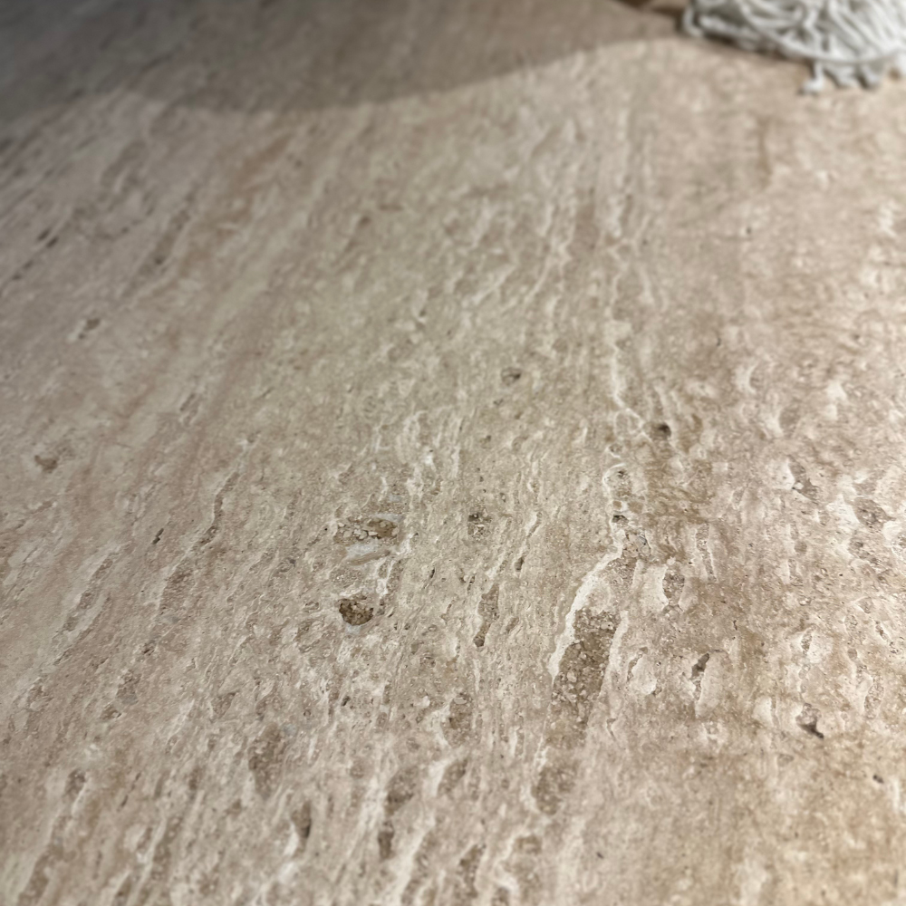 Detailfoto van een travertin tafelblad met natuurlijke aders en kleurnuances